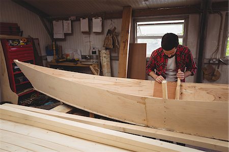 simsearch:6109-08764384,k - Man preparing wooden boat frame in boatyard Foto de stock - Sin royalties Premium, Código: 6109-08764374