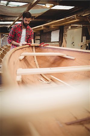 Man preparing wooden boat frame in boatyard Stock Photo - Premium Royalty-Free, Code: 6109-08764385
