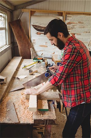 simsearch:6109-08764384,k - Man cutting a wooden plank at boatyard Foto de stock - Sin royalties Premium, Código: 6109-08764388