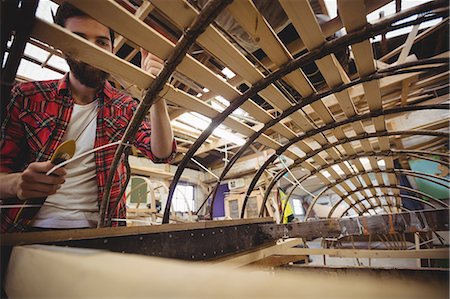 Man preparing a wooden boat frame at boatyard Stock Photo - Premium Royalty-Free, Code: 6109-08764398