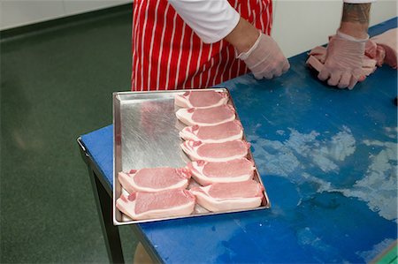 simsearch:6109-08764565,k - Mid section of butcher arranging steaks in tray at butchers shop Foto de stock - Sin royalties Premium, Código: 6109-08764485