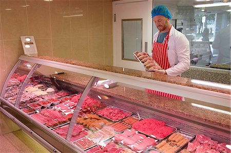 display of supermarket meat - Butcher standing at meat counter in butchers shop Stock Photo - Premium Royalty-Free, Code: 6109-08764491