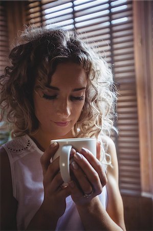 simsearch:6109-08764423,k - Close-up of beautiful woman having coffee in living room at home Stock Photo - Premium Royalty-Free, Code: 6109-08764404