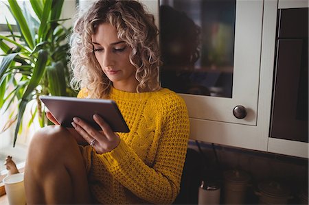 relaxing in the kitchen - Beautiful woman using digital tablet in kitchen at home Stock Photo - Premium Royalty-Free, Code: 6109-08764413