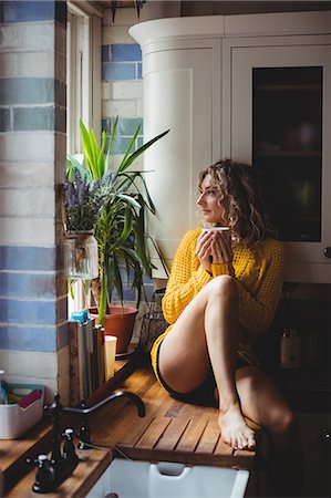 simsearch:6109-08945013,k - Beautiful woman having coffee in kitchen at home Stock Photo - Premium Royalty-Free, Code: 6109-08764411