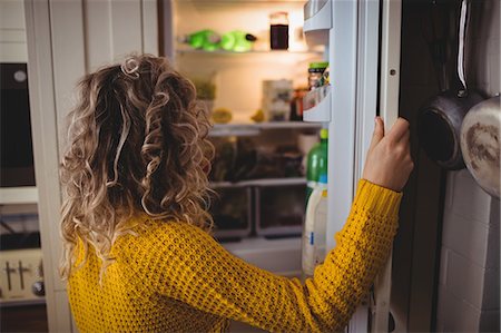Woman looking for food in refrigerator in kitchen at home Photographie de stock - Premium Libres de Droits, Code: 6109-08764415