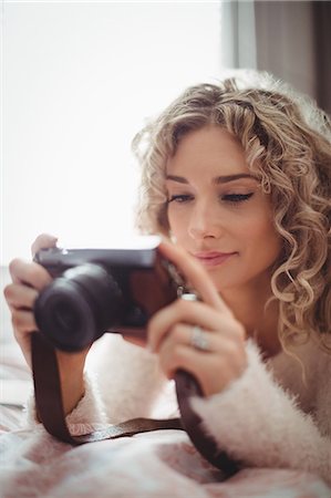 Woman looking photo on digital camera in bedroom at home Photographie de stock - Premium Libres de Droits, Code: 6109-08764437