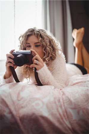 Woman looking photo on digital camera in bedroom at home Photographie de stock - Premium Libres de Droits, Code: 6109-08764436