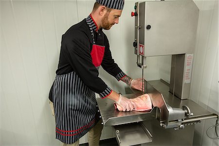 simsearch:6109-08764565,k - Butcher cutting pork in machine at butchers shop Foto de stock - Sin royalties Premium, Código: 6109-08764561