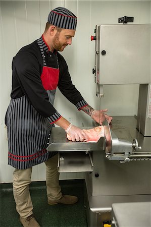 simsearch:6109-08764565,k - Butcher cutting pork in machine at butchers shop Foto de stock - Sin royalties Premium, Código: 6109-08764562