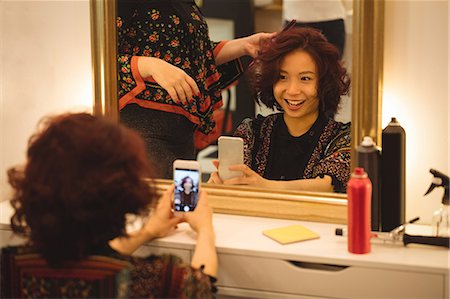 Stylish woman taking mirror selfie at hair salon Photographie de stock - Premium Libres de Droits, Code: 6109-08764579