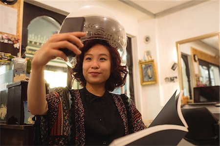 simsearch:400-08094595,k - Stylish woman taking a selfie while sitting under a hairdryer at hair salon Stock Photo - Premium Royalty-Free, Code: 6109-08764588