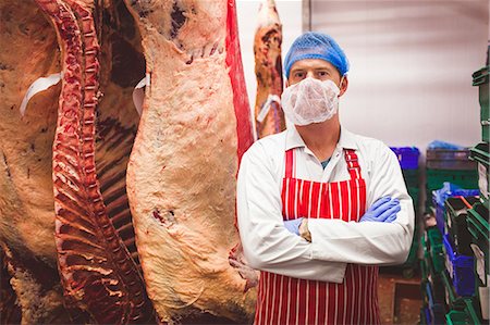 simsearch:6109-08764503,k - Portrait of butcher standing with arms crossed in meat storage room at butchers shop Stock Photo - Premium Royalty-Free, Code: 6109-08764521