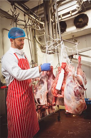 Butcher sticking barcode stickers on red meat in storage room at butchers shop Foto de stock - Sin royalties Premium, Código: 6109-08764527