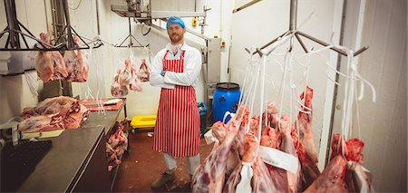simsearch:6122-07698263,k - Portrait of butcher standing with arms crossed in meat storage room at butchers shop Stock Photo - Premium Royalty-Free, Code: 6109-08764525