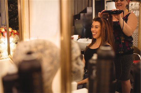 raddrizzare - Woman smiling while getting her hair straightened at hair saloon Fotografie stock - Premium Royalty-Free, Codice: 6109-08764644