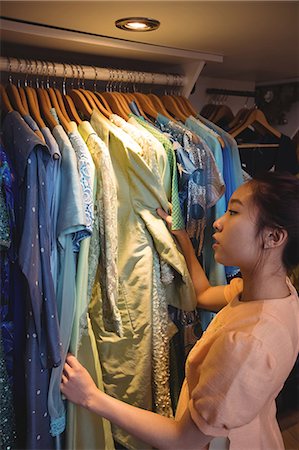 simsearch:6116-07235750,k - Woman selecting a clothes from hanger at boutique store Foto de stock - Sin royalties Premium, Código: 6109-08764685