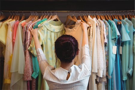 simsearch:6109-08928895,k - Woman selecting a clothes from hanger at boutique store Foto de stock - Sin royalties Premium, Código: 6109-08764686