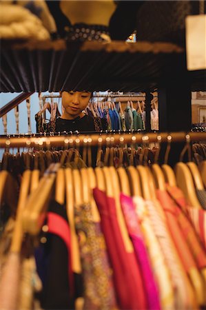 simsearch:6116-07235750,k - Woman selecting a clothes on hanger at apparel store Foto de stock - Sin royalties Premium, Código: 6109-08764688