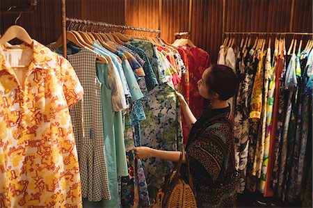 simsearch:6116-07235750,k - Woman selecting a clothes on hanger at apparel store Foto de stock - Sin royalties Premium, Código: 6109-08764691