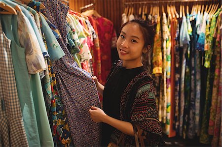 simsearch:6116-07235750,k - Portrait of smiling woman selecting a clothes on hanger at apparel store Foto de stock - Sin royalties Premium, Código: 6109-08764692