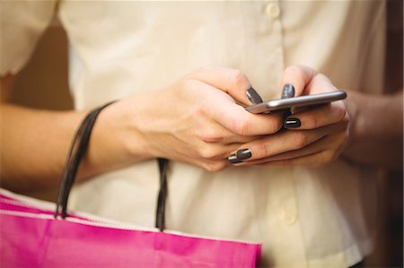 shopper texting - Mid section of woman using mobile phone while shopping in boutique store Stock Photo - Premium Royalty-Free, Code: 6109-08764623