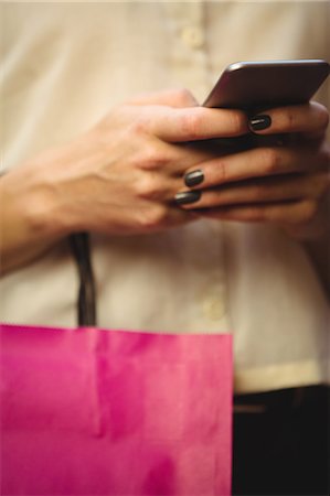 shopper texting - Mid section of woman using mobile phone while shopping in boutique store Stock Photo - Premium Royalty-Free, Code: 6109-08764624