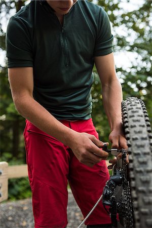simsearch:6109-08764763,k - Male cyclist repairing his bicycle in forest on a sunny day Stock Photo - Premium Royalty-Free, Code: 6109-08764744