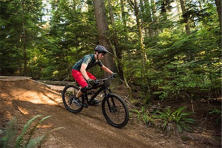 simsearch:6109-08928555,k - Male cyclist cycling in forest on a sunny day Photographie de stock - Premium Libres de Droits, Code: 6109-08764754