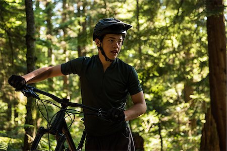 simsearch:6109-08928532,k - Male cyclist walking with mountain bike in forest Photographie de stock - Premium Libres de Droits, Code: 6109-08764761