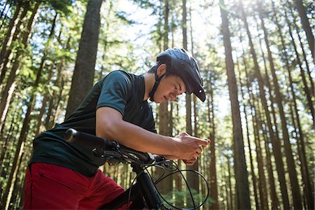 simsearch:6109-08764763,k - Male cyclist using mobile phone in forest on a sunny day Stockbilder - Premium RF Lizenzfrei, Bildnummer: 6109-08764778