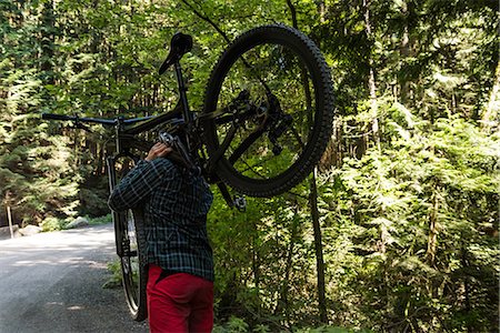 simsearch:6109-08764763,k - Male cyclist carrying mountain bike while walking in park Stock Photo - Premium Royalty-Free, Code: 6109-08764786