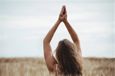 simsearch:6118-08220580,k - Woman with hands raised over head in prayer position in field on a sunny day Stock Photo - Premium Royalty-Free, Code: 6109-08764789