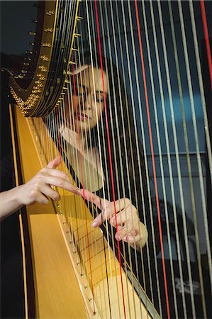 simsearch:6109-08764943,k - Attentive woman playing a harp in music school Foto de stock - Sin royalties Premium, Código: 6109-08764707