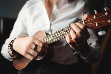 Mid-section of woman playing a guitar in music school Foto de stock - Royalty Free Premium, Número: 6109-08764721