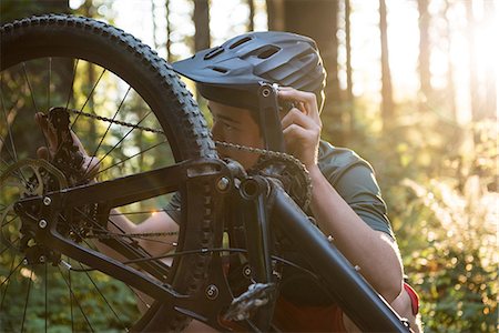 simsearch:6109-08764763,k - Male cyclist repairing his bicycle in forest on a sunny day Stock Photo - Premium Royalty-Free, Code: 6109-08764739