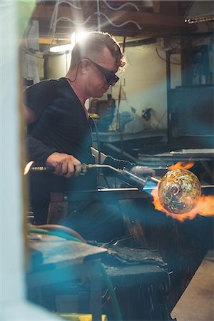 simsearch:614-06973581,k - Glassblower giving final touch to a piece of glass with glassblowing torch at glassblowing factory Stock Photo - Premium Royalty-Free, Code: 6109-08764843