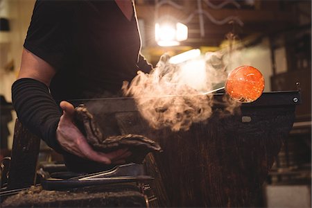 simsearch:400-05882411,k - Glassblower shaping molten glass piece with a wet cloth at glassblowing factory Foto de stock - Sin royalties Premium, Código: 6109-08764848