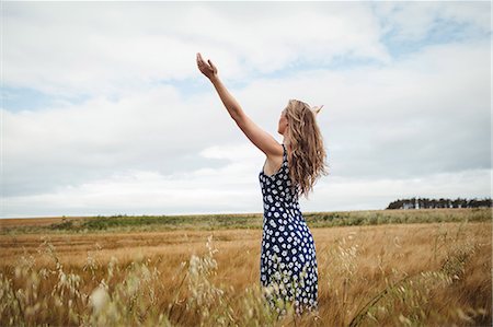 simsearch:6113-07543089,k - Rear view woman standing with arms outstretched in field Photographie de stock - Premium Libres de Droits, Code: 6109-08764821