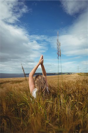 simsearch:6113-08220455,k - Woman with hands raised over head in prayer position in field on a sunny day Stock Photo - Premium Royalty-Free, Code: 6109-08764828