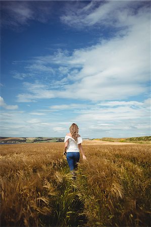 simsearch:400-03920699,k - Rear view of woman walking through wheat field on a sunny day Photographie de stock - Premium Libres de Droits, Code: 6109-08764833