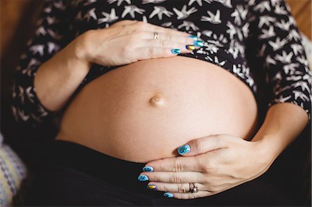 simsearch:6109-08764905,k - Mid section of pregnant woman relaxing in living room at home Photographie de stock - Premium Libres de Droits, Code: 6109-08764901