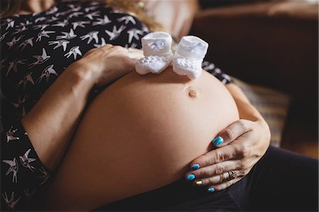 simsearch:6109-08764905,k - Pair of baby socks on pregnant woman stomach in living room at home Photographie de stock - Premium Libres de Droits, Code: 6109-08764909