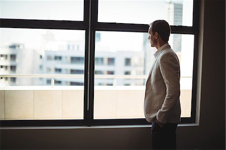 simsearch:693-07456224,k - Thoughtful businessman looking through window at office Stock Photo - Premium Royalty-Free, Code: 6109-08765094