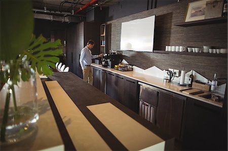 Businessman preparing coffee in coffee maker at cafeteria Foto de stock - Royalty Free Premium, Número: 6109-08765147