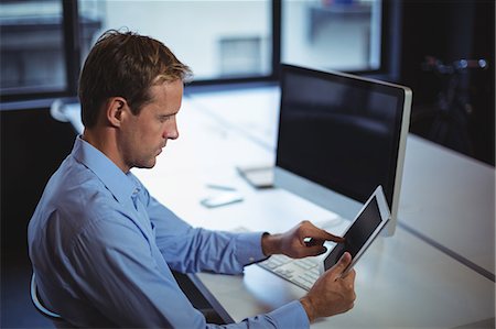 Businessman using digital tablet and desktop pc in office Stock Photo - Premium Royalty-Free, Code: 6109-08765165