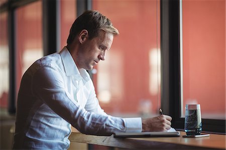 simsearch:6102-07768484,k - Businessman writing in diary at desk in office Stock Photo - Premium Royalty-Free, Code: 6109-08765124