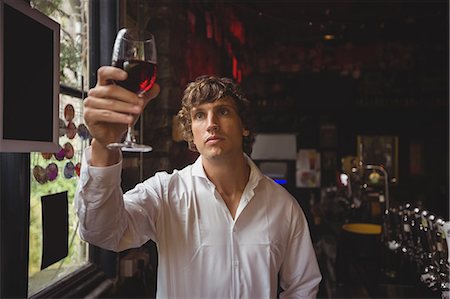 Bartender looking at glass of red wine at bar counter Stock Photo - Premium Royalty-Free, Code: 6109-08782670