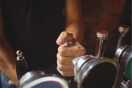 Close-up of bar tender filling beer from bar pump at bar counter Fotografie stock - Premium Royalty-Free, Codice: 6109-08782631