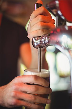 Close-up of bar tender filling beer from bar pump at bar counter Stock Photo - Premium Royalty-Free, Code: 6109-08782635